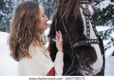 Woman with brown hare hugging beautiful  brown horse outdoor in winter day