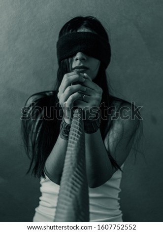 Creative portrait, woman tied with red cloth and blindfolded with blue cloth displaying the feeling of pain, prison, fear and prayer. Photo to show how you feel in depression. Art portrait
