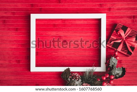 White photo frame, gift, winter pine cones, flower, leaves on old red wooden background. Valentine day, Christmas, Mother day, Wedding anniversary, Greeting card concept. Top view with copy space.