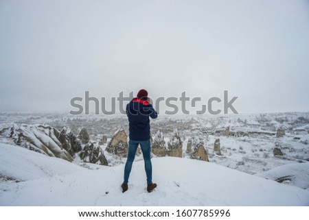 camera man with winter coat takes landscape photographs in Cappadocia winter