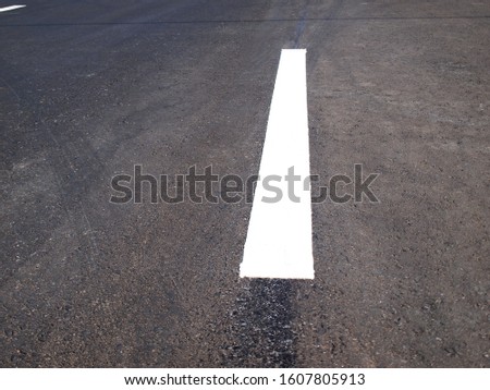 Closeup - White stripe on Asphalt Road On the background of the black asphalt road. Selective focus