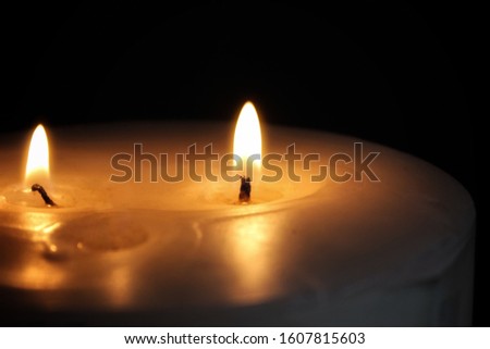 An artistically enhanced photograph of a lit candle burning in a dark room. 