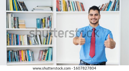 Hispanic hipster businessman with copy space showing thumbs up at office