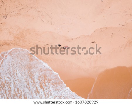 Top view of sandy beach with foam, sand texture, beautiful waves, person with bicycle aerial drone shot.