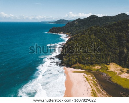 Amazing aerial top view of sandy beach. Summer landscape with mountains, green forest, azure water, sandy beach and blue sky in bright sunny day. Travel background.