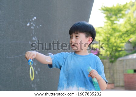 In the playground, a child in blue is playing with a bubble toy in his hand.