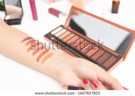 Closeup of hands of woman makeup artist testing eyeshadow different colors on her hand.