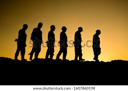 Silhouette of oilfield workers at sunset