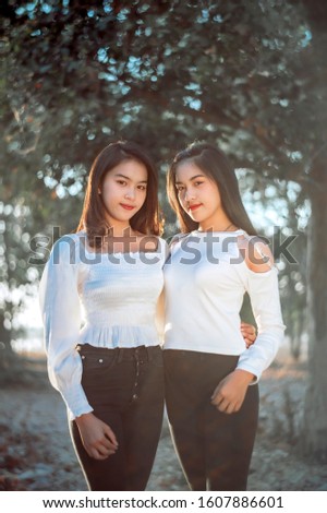  Two Twin teenage girls young woman laughting and having fun near the garden at sunset time