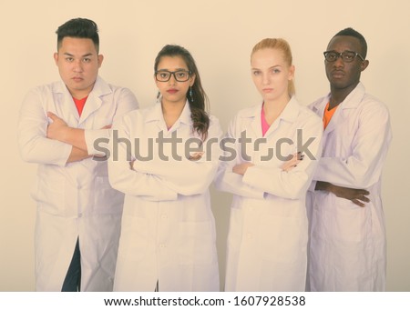 Studio shot of diverse group of multi ethnic doctors with arms crossed together