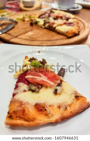 round pide or Turkish pizza with cheese, sujuk and different types of meat on a wooden tray. selective focus. small focus area