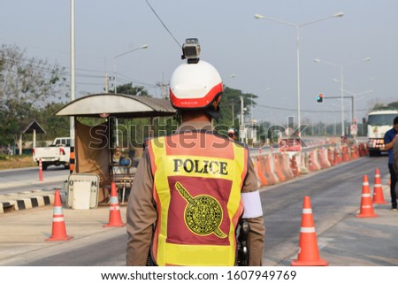 traffic police stand beside the road to service the passers on road at checkpoint in Thailand, Picture not clear, Have blur.