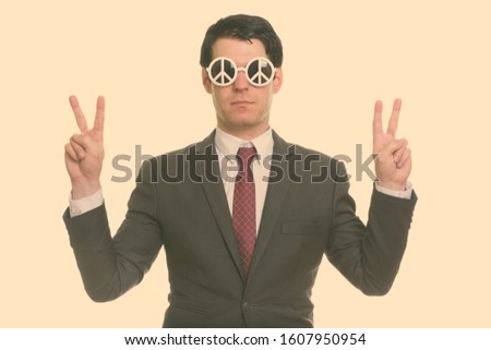 Handsome businessman wearing sunglasses with peace sign and doing peace sign with both hands