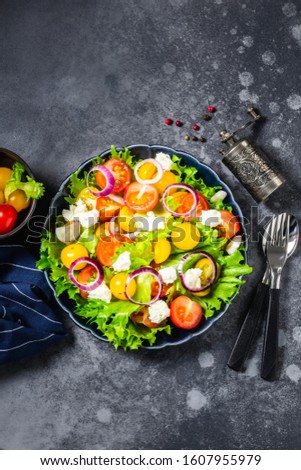 Fresh rainbow salad with feta cheese and lemon dressing on dark background. Top view, space for text.
