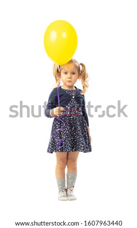 portrait of isolated blonde little girl holding yellow ballon
