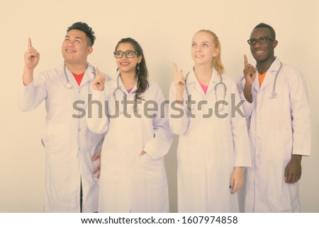 Diverse multi ethnic group of happy doctors pointing up together