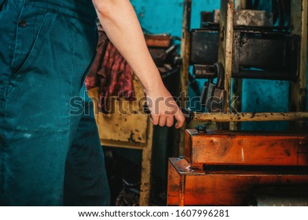 Gender equality. A woman in uniform working near the machine, hands close-up. In the background, a blue wall and tools