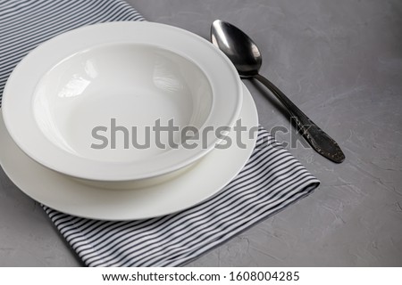 Dining layout. Beautiful serving on a gray linen napkin. A plate for soup or a side dish. Light gray background and white plates.
