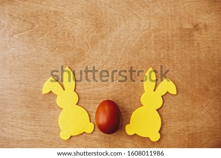 Stylish easter egg and yellow bunny on rustic wooden table flat lay, space for text. Natural dyed easter egg and rabbit decorations on wooden background. Holiday card