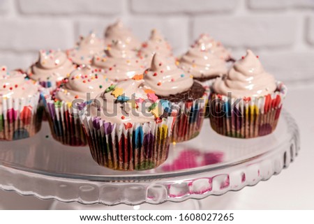 Birthday concept. Delicious cupcakes with colorful decorations on cake plate. Horizontal orientation, hard light.
