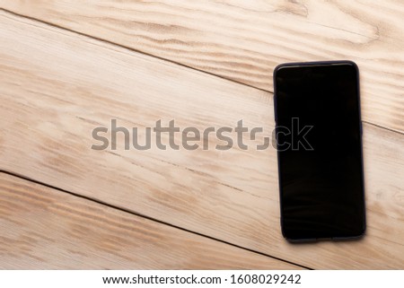 Mobile phone iphon style mockup with black screen on wooden background. Copy space