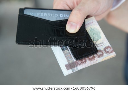 man hands holding wallet with credit cards and stack of money.