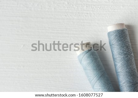 Sewing gray threads on cardboard spools on white painted wood background. Crafts hobbies local artisan business concept. Clean minimalist style copy space