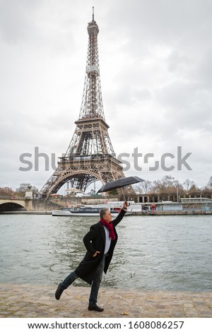 Man stands with an umbrella on the river Bank against the background of the Eiffel tower