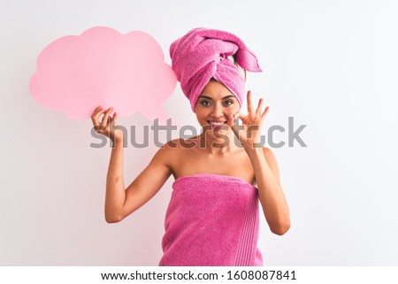 Beautiful woman wearing shower towel holding speech bubble over isolated white background doing ok sign with fingers, excellent symbol