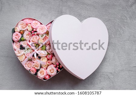 Heart shape gift box and bouquet. fresh flowers a gift in the shape of a heart. roses in a box heart close-up with a blurred background on a white  table. pink roses, yellow roses