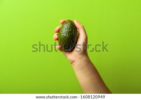 avocado in a hand of woman green background. healthy food concept