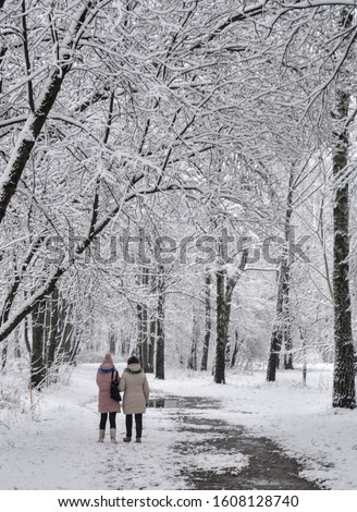 two girls walking in the snowy park winter landscape Christmas time
