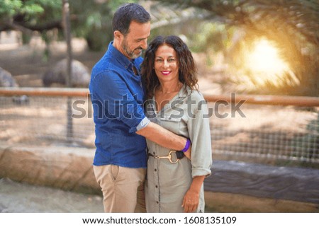 Middle age beautiful couple smiling happy and confident at town park. Standing with smile on face and hugging