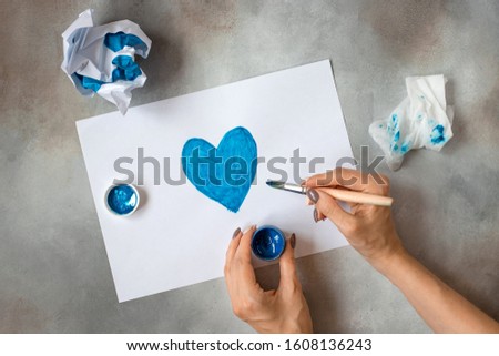 woman's hands holding a jar with blue paint and draws a picture. creativity, painting