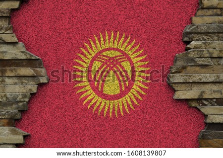 Kyrgyzstan flag depicted in paint colors on old stone wall closeup. Textured banner on rock wall background