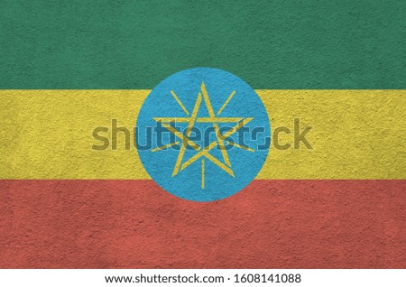 Ethiopia flag depicted in bright paint colors on old relief plastering wall. Textured banner on rough background