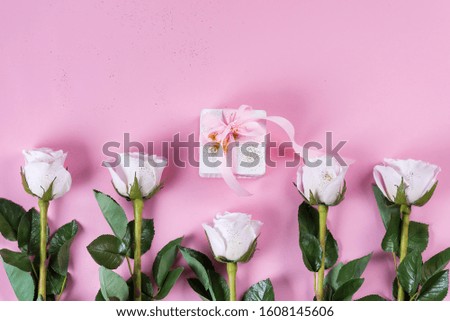 Pink rose and white gift box with pink ribbon on pink background