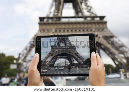 Woman in Paris taking pictures in front of Eiffel Tower with her Tablet PC