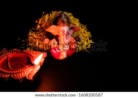 high angle shot of beautiful ganesha statue with clay lamp glowi