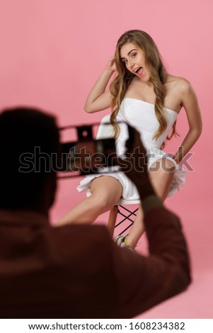 cute smiling model woman posing in front of photographer in studio