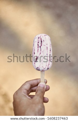 Hand holding popsicle on background.