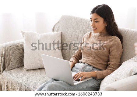 Find job online. Asian girl searching for work opportunities, using laptop at home