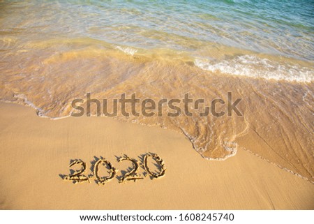 2020 summer beach holiday season written on golden sand washed away wave - new season lettering on sand - numbers 2020 year travel vacation sandy wavy water yellow blue azure aquamarine turquoise