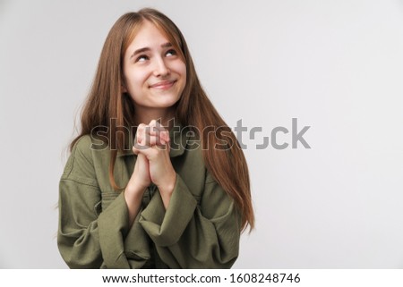 Photo of caucasian happy woman looking upward and holding palms together isolated over white background