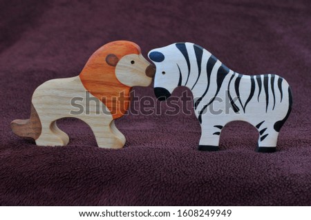 Lion kissing a Zebra. Wooden toys on a brown background.