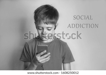 A young man in a t-shirt looks at his mobile phone. Monochrome, black-and-white photography.Copy space. Internet addiction or social addiction.