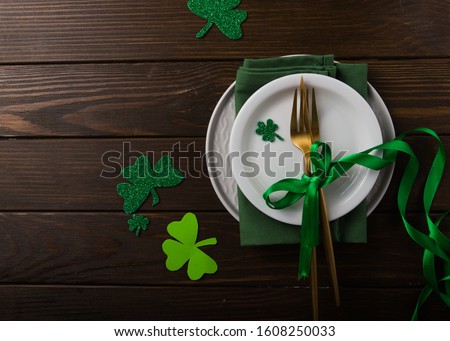 St. Patrick's Day green Shamrocks with fork, spoon, and napkin on rustic brown wood board background with room or space for copy, text, words. Square
