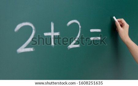 Two add two written on chalkboard.