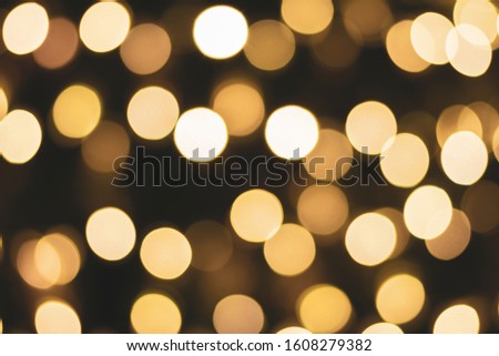 Abstract beige bokeh on a black background. Defocused abstract lights christmas background. Selective focus. Blur