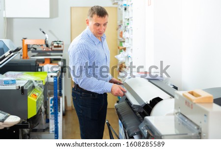 Man uses plotter in small printing shop